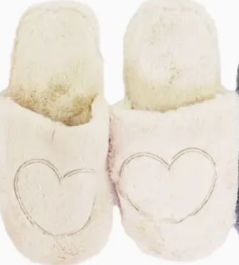 Pair of cream-colored slippers with heart designs on a white background