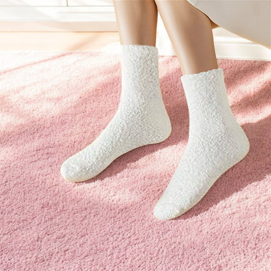 White fuzzy socks on woman with bathrobe on and pink carpet