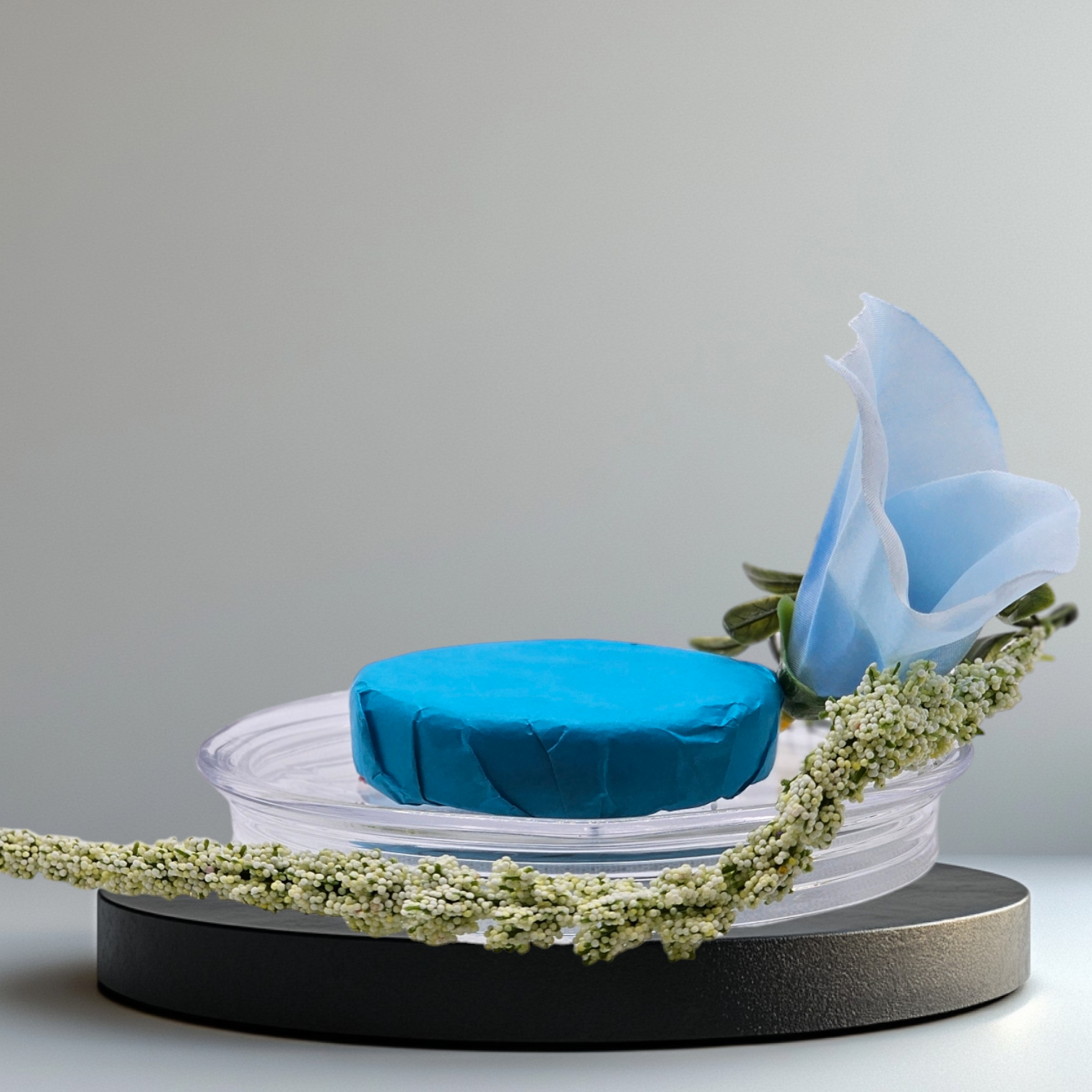 Verity Collectives Lucid Dreaming Shower Steamer wrapped in blue tissue paper with a blue flower and light bluish grey background