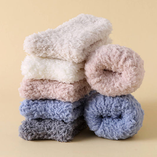 Stack of fluffy donut-shaped bath bombs in various colors on a beige background