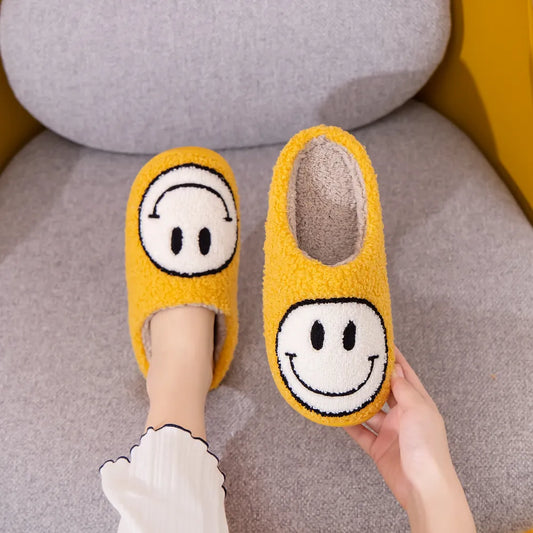 Yellow furry slippers with a while smiley face on them