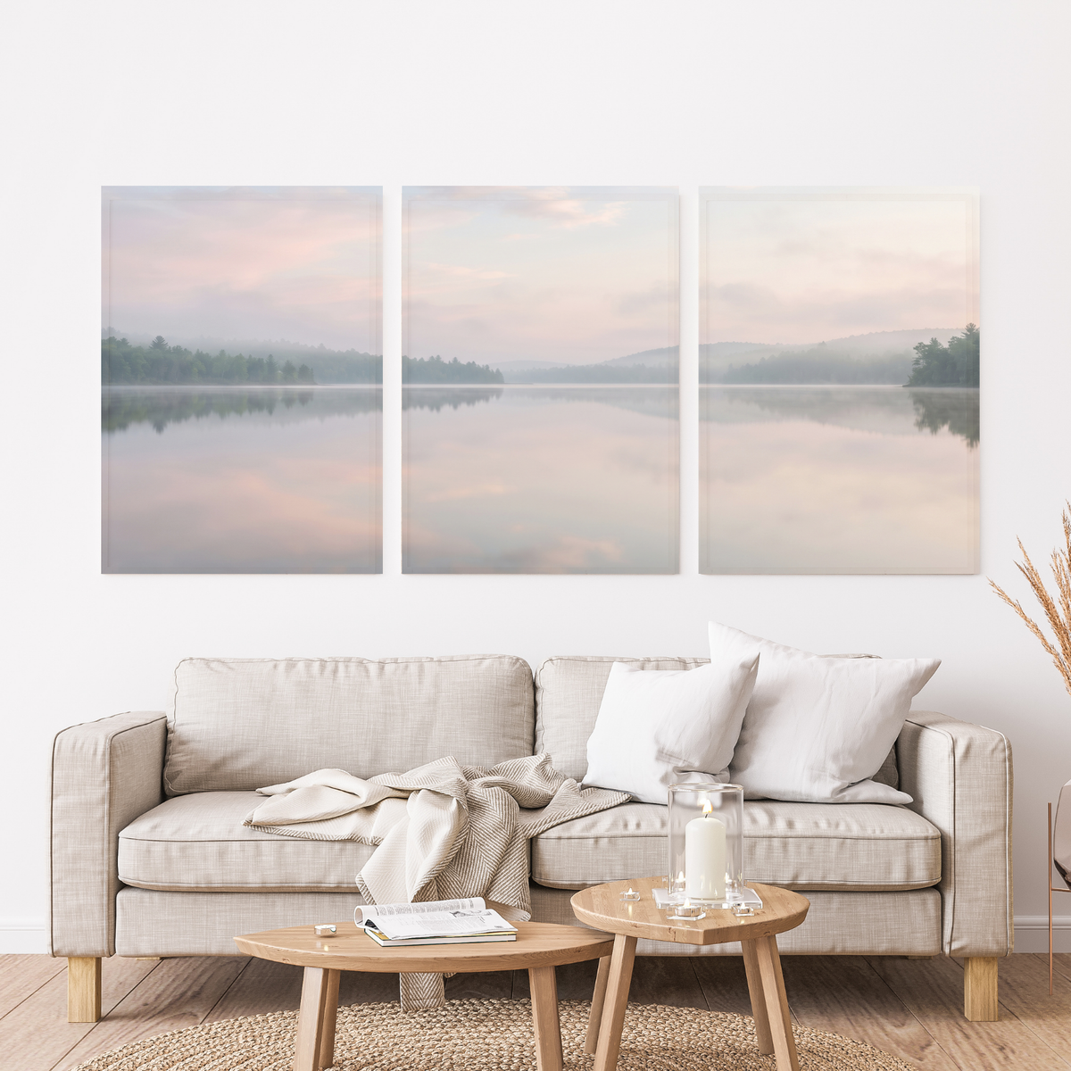 Three-panel misty lake canvas set with blush and pale blue sky, pine-covered shores, and mirror-still water with white couch below panels