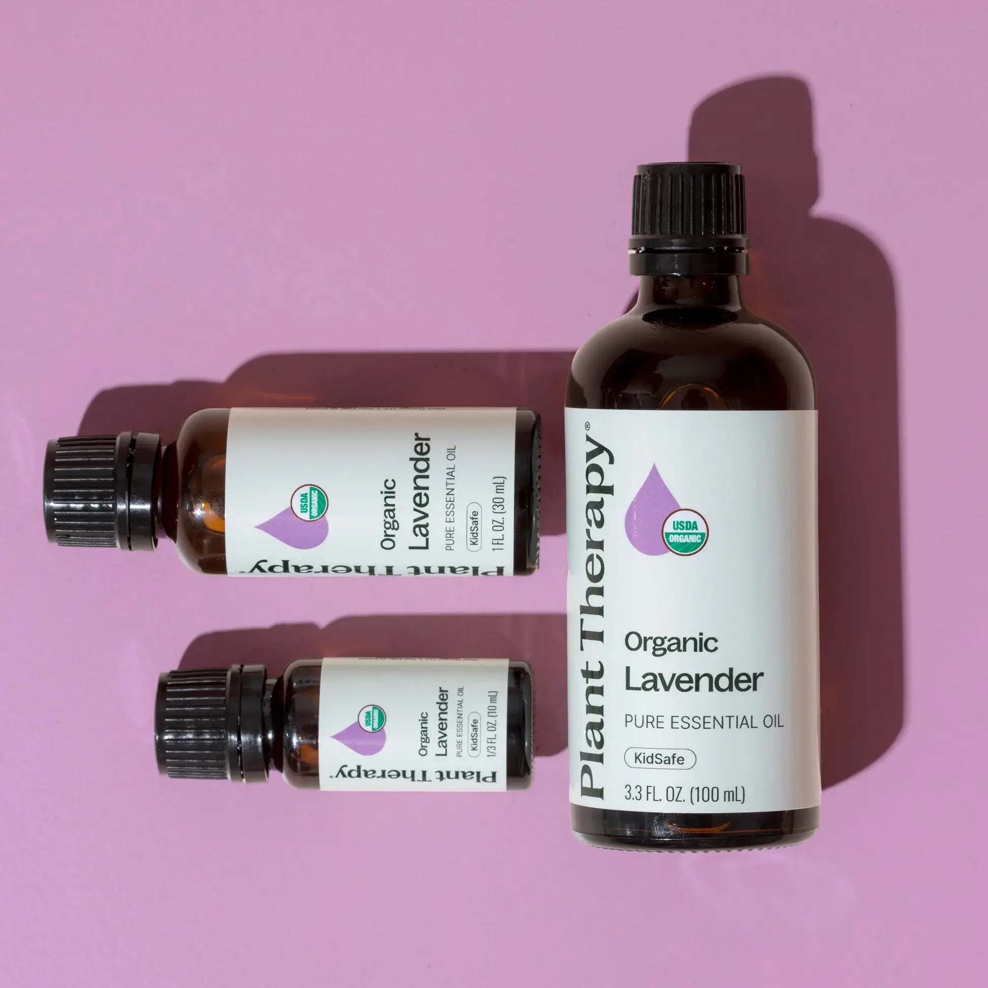 three different sizes of bottles for lavender organic oil against lavender background